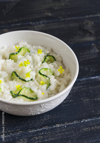 risotto with zucchini in a white bowl on a dark wooden surface