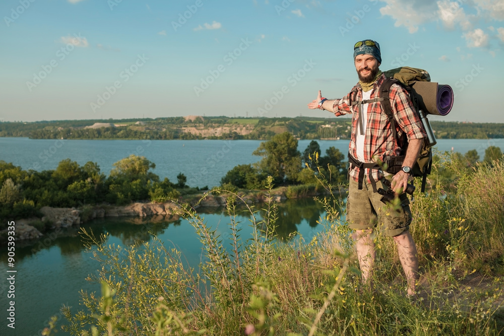 Young caucasian man with backpack standing on the top of hill Young caucasian man with backpack standing on the top of hill