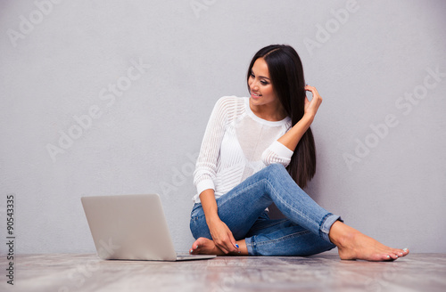 Happy girl sitting on the floor with laptop
