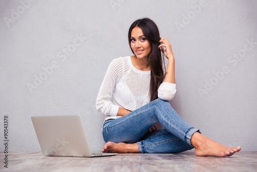 Cheerful woman sitting on the floor with laptop