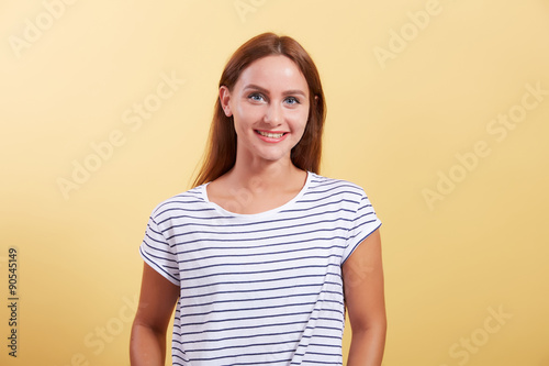 the red-haired beautiful young girl smiles on a yellow backgroun