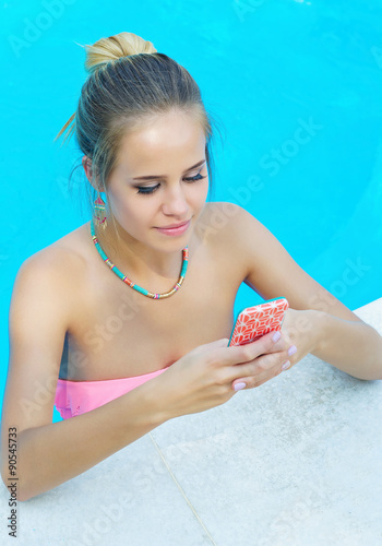 Portrait of a young adorable woman chatting on her cell phone in the swimming pool