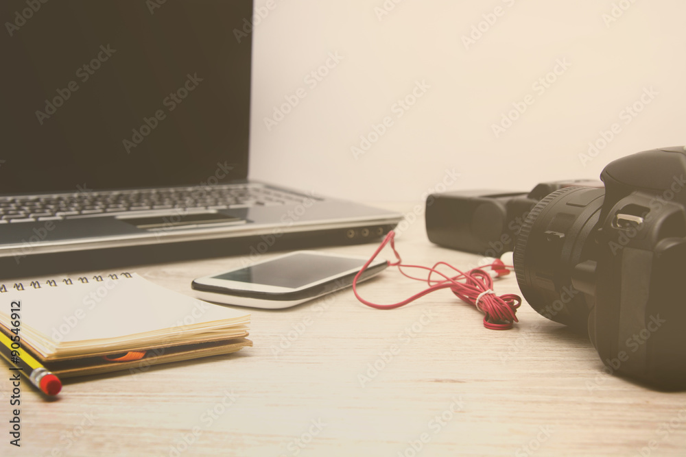 Laptop, digital camera, mobile phone, notebook and earphones on wood table Laptop, digital camera, mobile phone, notebook and earphones on wood table