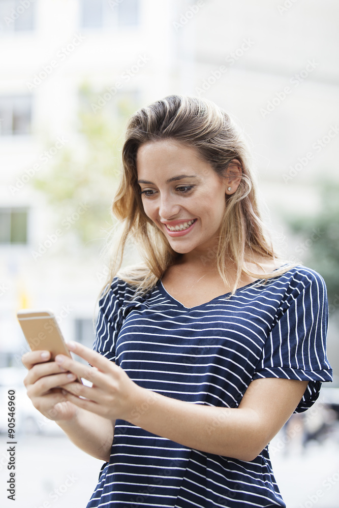 Fototapeta premium A portrait of a smiling beautiful woman texting with her phone