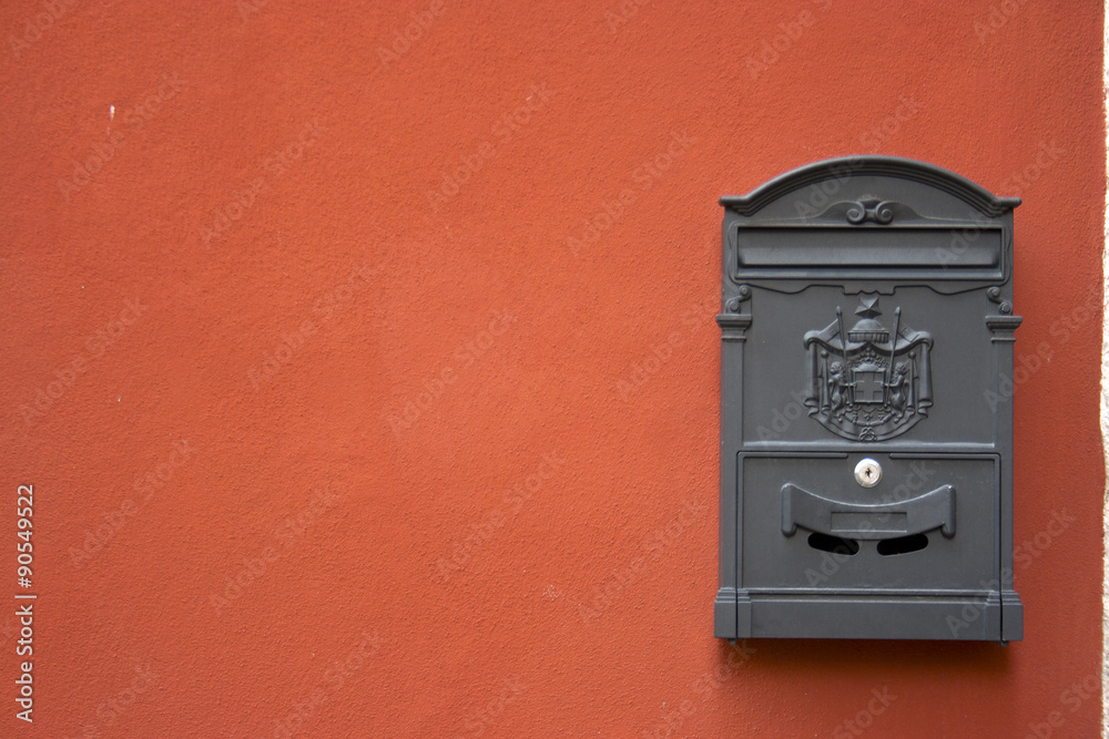 grey mailbox on a red wall