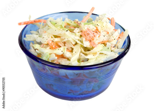 Coleslaw in Blue Bowl – Fresh coleslaw salad, with carrots, cabbage, and coleslaw dressing, in a blue glass bowl. On a white background.
