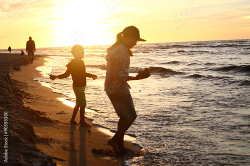 Wakacje nad morzem. Dzieci bawią się na brzegu morza podczas zachodu słońca