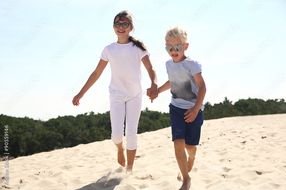 Szczęśliwe dzieci biegają po złotej plaży - obrazy, fototapety, plakaty 