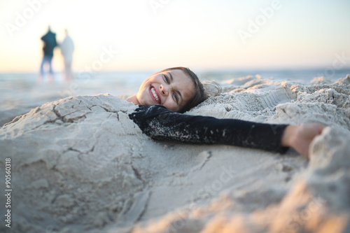 Plaża,radość i zabawa. Roześmiana, szczęśliwa dziewczynka leży na piaszczystej plaży