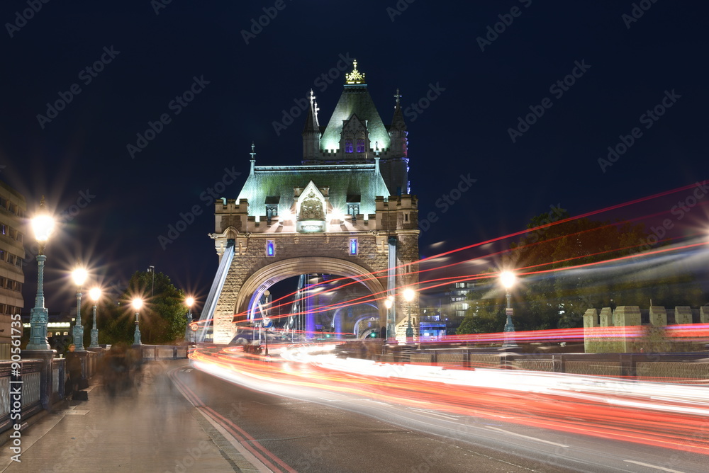 Fototapeta premium World famous Historic Tower Bridge in London, UK at night with light trail of red bus and cars, long exposure artistic shot