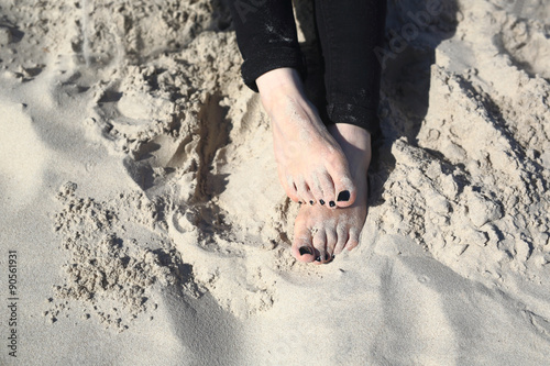 Relaks na plaży. Stopy kobiety zasypane w piasku na plaży