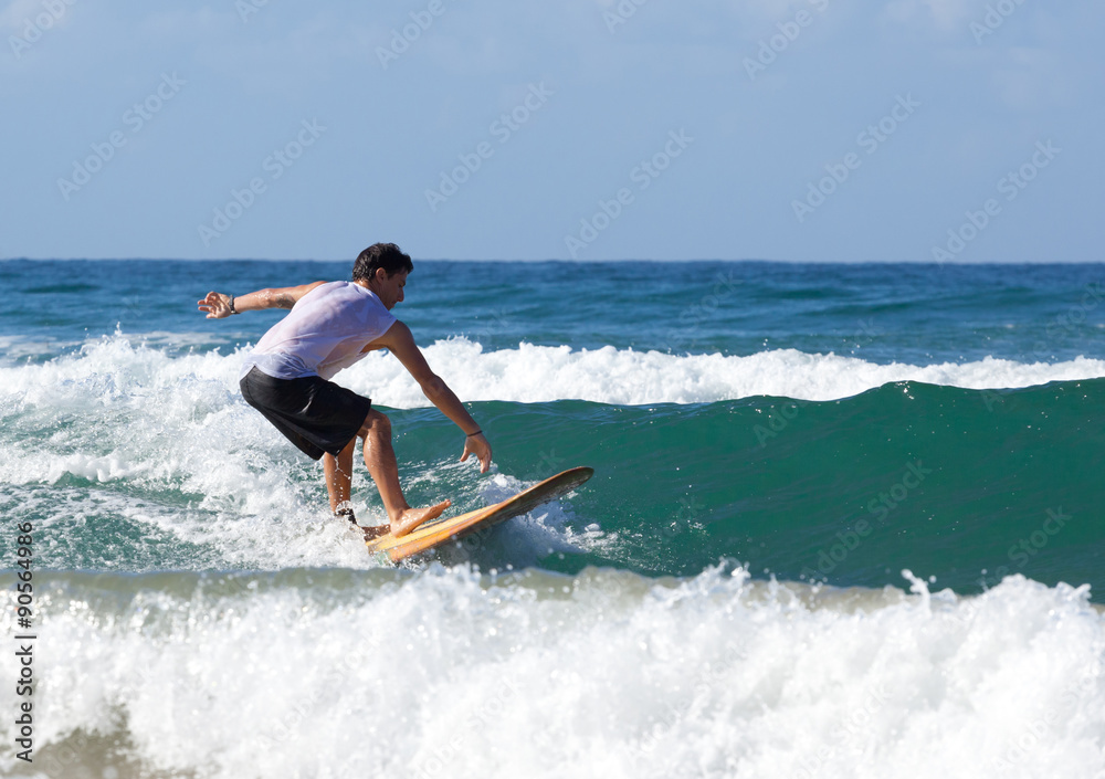 Surfer on longboard rides a wave in the sea