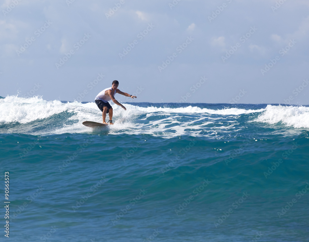 Surfer on longboard rides a wave in the sea