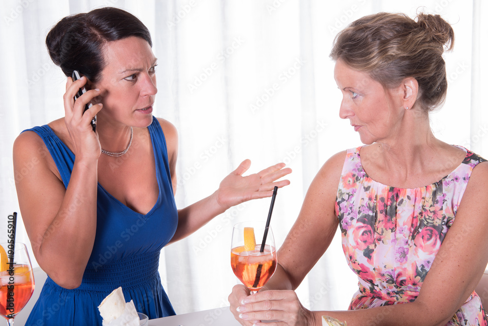 two attractive women - one is concerned about phone call two attractive women - one is concerned about phone call