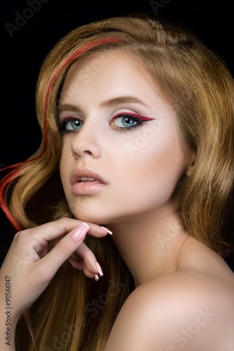 Beauty portrait of young pretty girl with red and black make-up arrows