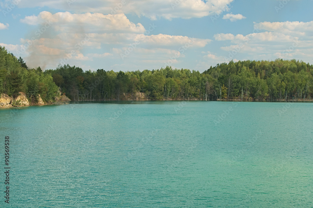 Lake with green water and trees, smoke