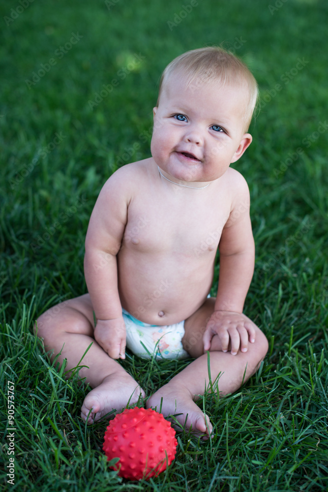Boy sitting on grass in park, playing with balls and smiling. Boy sitting on grass in park, playing with balls and smiling.