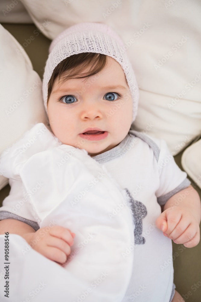 Portrait of baby girl with hat laying on bed