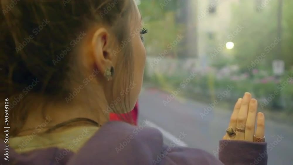 Girl looks out train window deep in thought