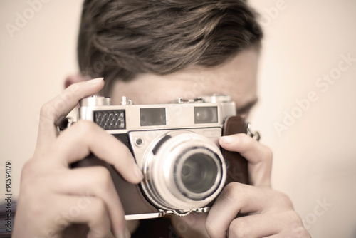 Boy holds retro style 35mm camera ready to take a picture