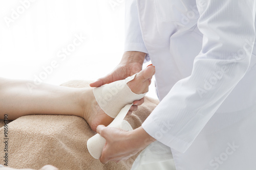Fotografie The doctor has wrapped taping in the patient's leg
