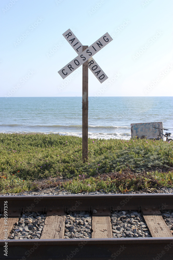 Rail Road Crossing with Train Tracks, Ocean and Blue Sky Background Rail Road Crossing with Train Tracks, Ocean and Blue Sky Background