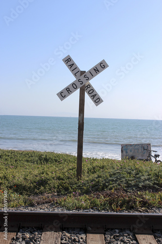 Rail Road Crossing Sign with Tracks, Ocean and Blue Sky