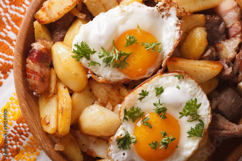  fried potatoes with meat, bacon and eggs close-up horizontal top view 
