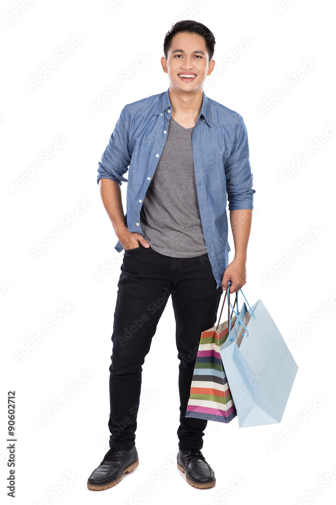Young asian man holding shopping bags, full body