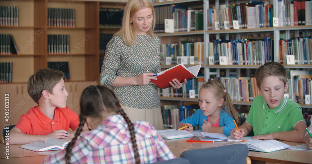 Experienced teacher working with elementary students in literature class 