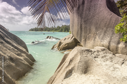 Big granite boulders rocks and palm leafs. The place is Anse Source d'Argent beach, in la Région, la Digue, Seychelles.