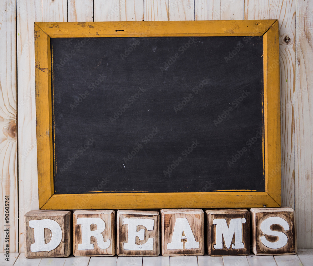 Chalkboard and DREAMS sign made of wooden blocks on wooden backg