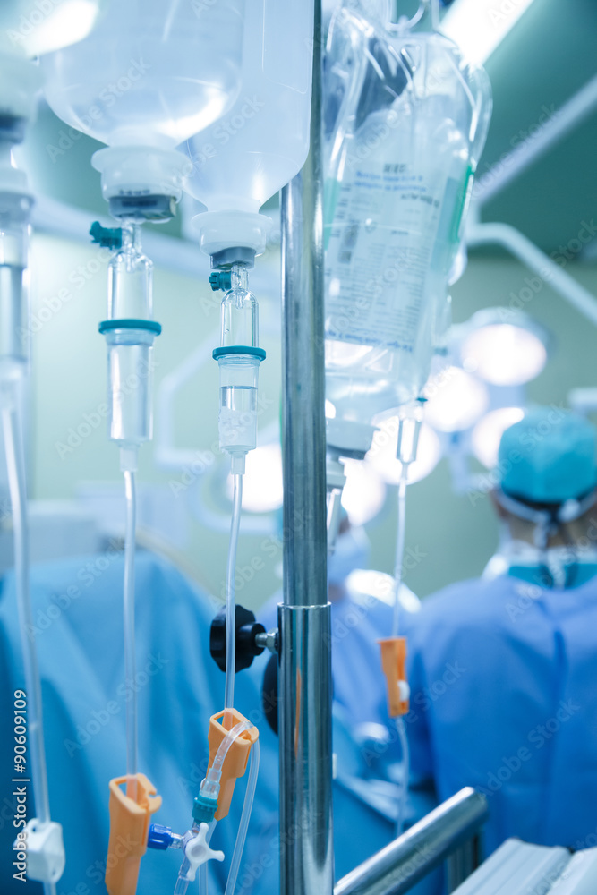 IV bags and bottles hanging on poles during a real surgery