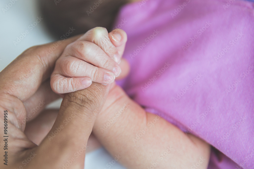 newborn baby holding finger, close up