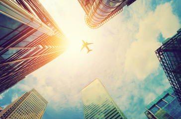 Airplane flying over modern business skyscrapers. Transport, travel.