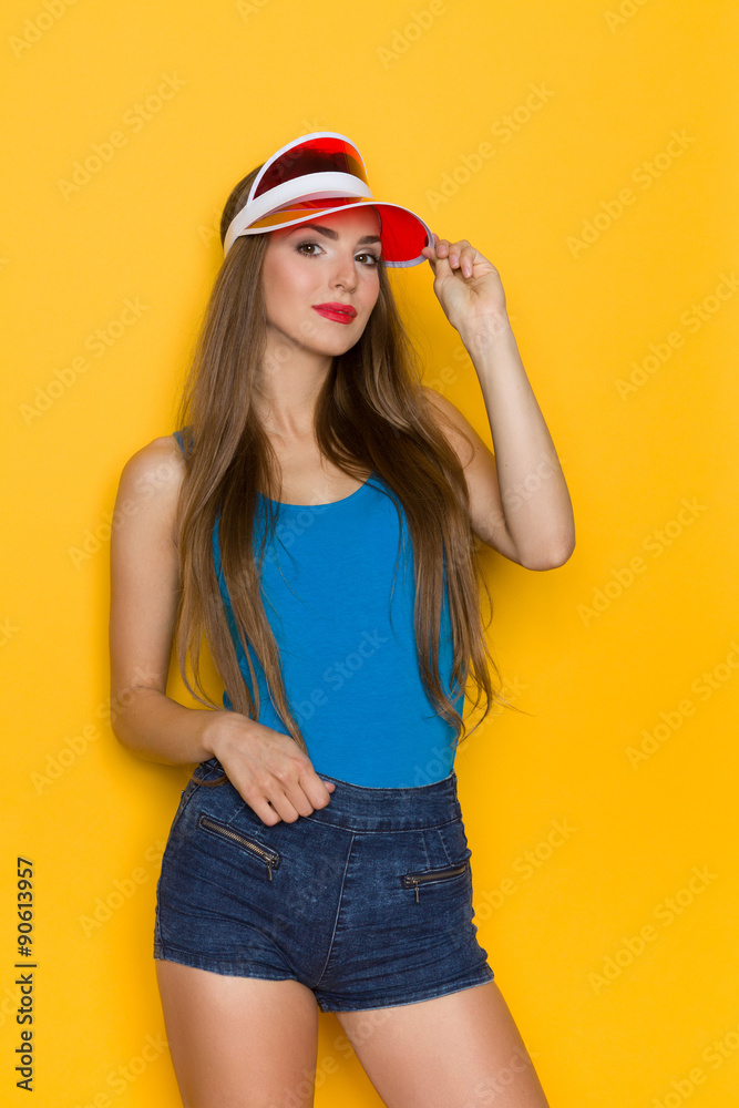 Beautiful Woman In Red Sun Visor. Three quarter length studio shot on yellow background. Beautiful Woman In Red Sun Visor. Three quarter length studio shot on yellow background.