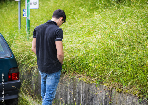 Photo Young Man Pissing at the Grassy Roadside