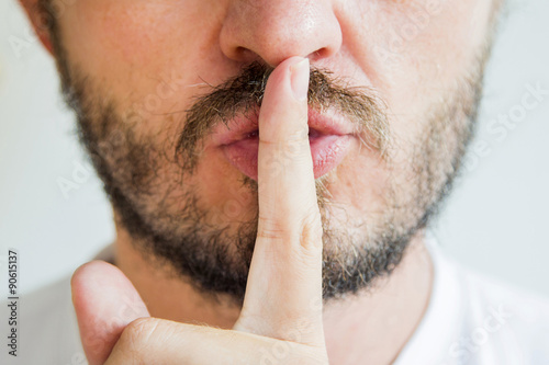 Bearded man making silence gesture, pst, shh, face detail photo