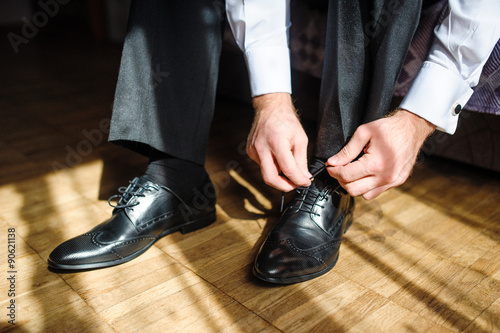 Business man tying shoe laces on the floor