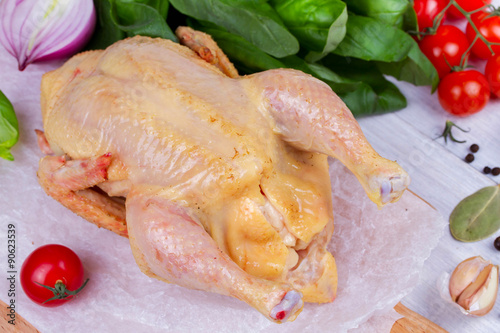 Whole fresh raw chicken prepared for roast with thyme and tomatoes cherry photo