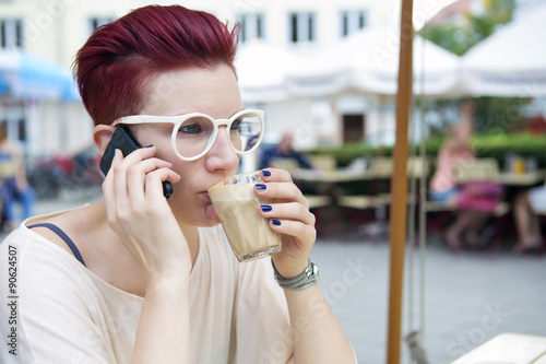 red-haired woman drinking coffee and talking on the phone