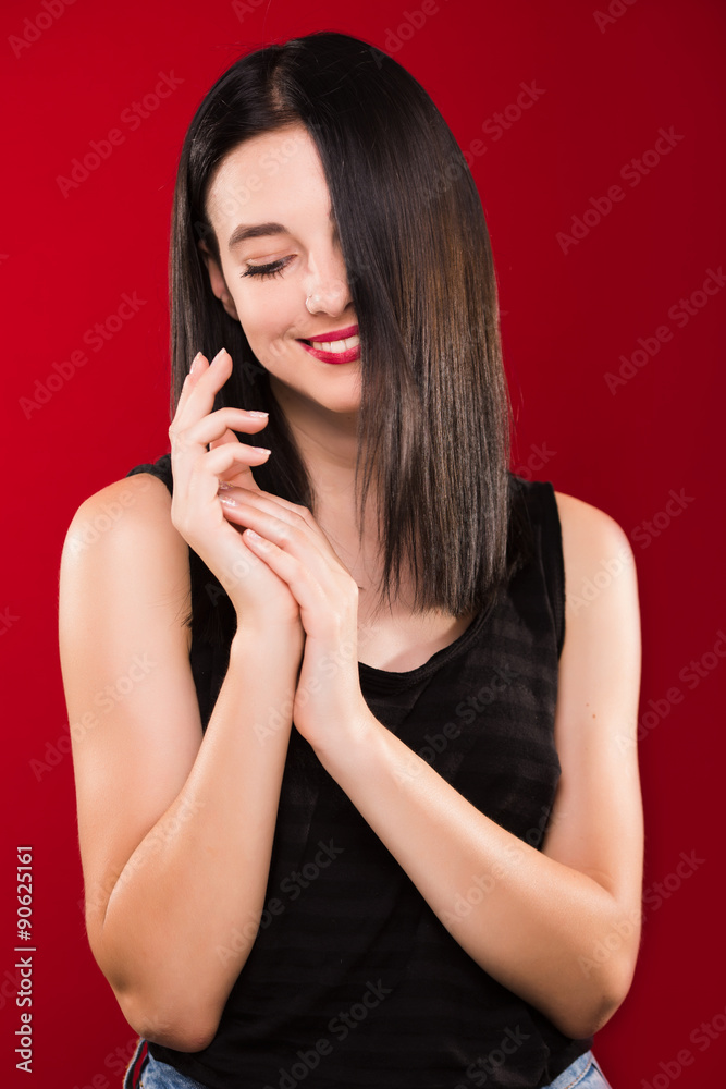 Charming young woman standing on the red background and smiling Charming young woman standing on the red background and smiling