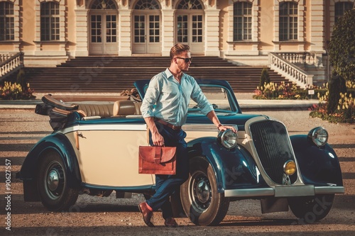 Confident wealthy young man with briefcase near classic convertible © Nejron Photo