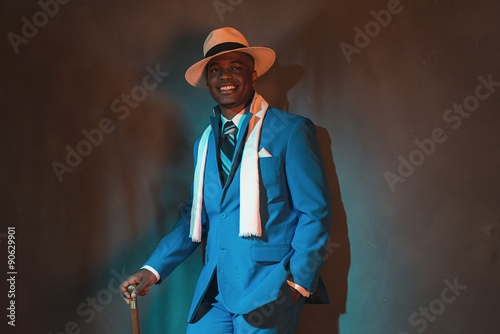African american dandy man in blue suit and straw hat. Holding c