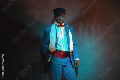 Retro african american man in blue suit wearing blue cap. Leanin