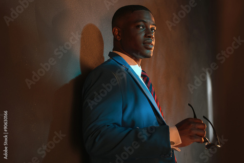 Obraz na plátně Retro african american businessman in blue suit holding sunglass