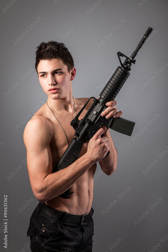 Handsome bare-chested soldier is holding a rifle Handsome bare-chested soldier is holding a rifle