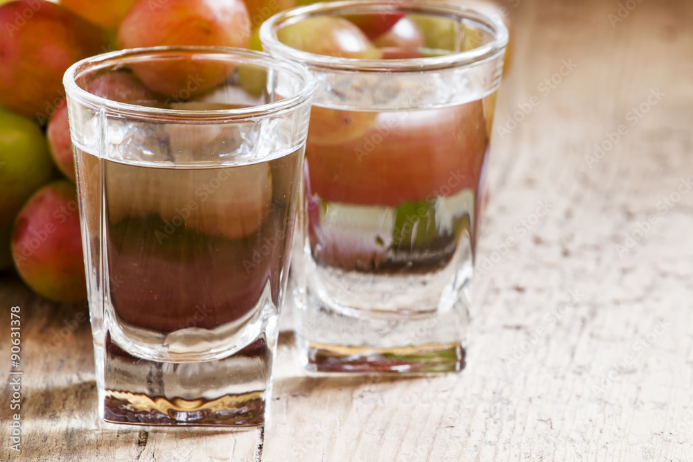 Grappa in a small glass and ripe grapes on old wooden table, sel Grappa in a small glass and ripe grapes on old wooden table, sel