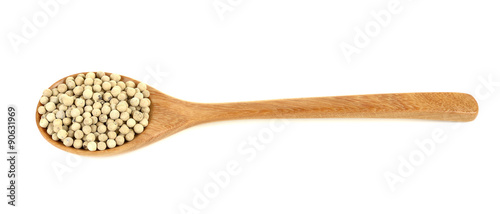 White pepper in wooden spoon on a white background