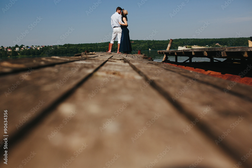 Hugging man and woman in love on wooden pier